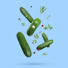 Image of Ripe cucumbers, herbs and spices falling on light blue background