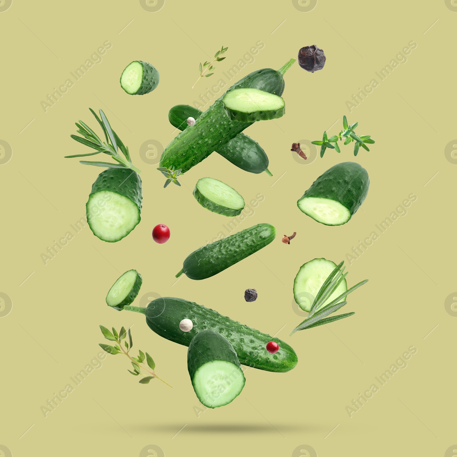 Image of Ripe cucumbers, herbs and spices falling on dark yellow background