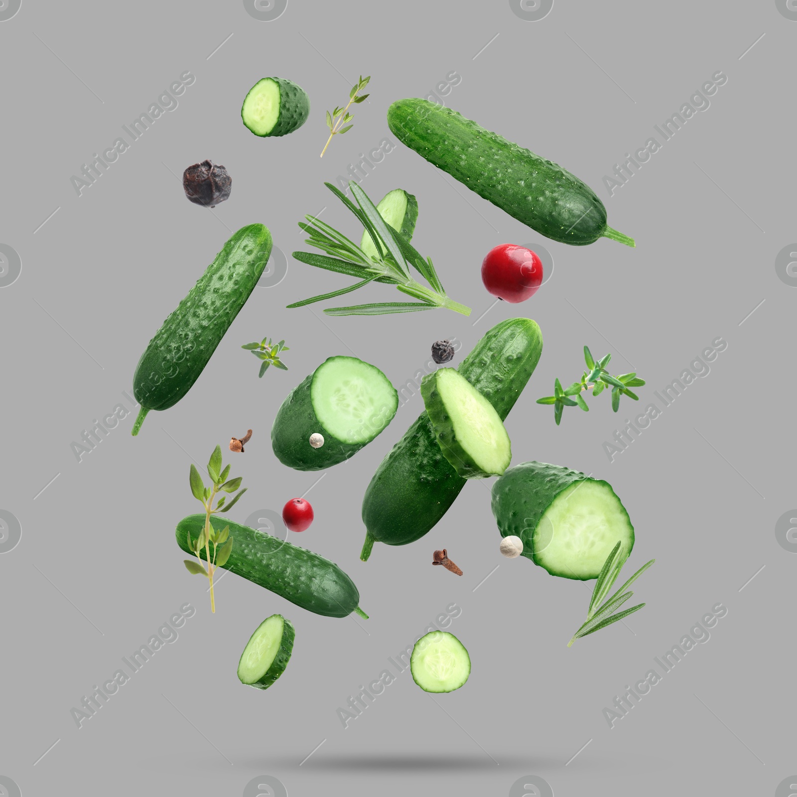 Image of Ripe cucumbers, herbs and spices falling on grey background