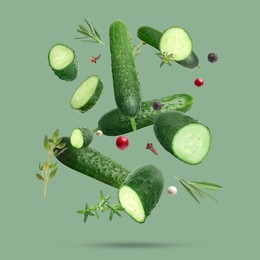 Image of Ripe cucumbers, herbs and spices falling on green background