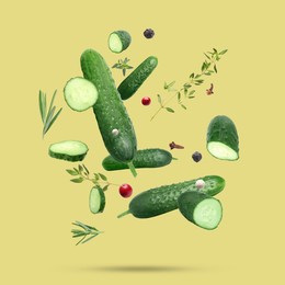 Image of Ripe cucumbers, herbs and spices falling on dark yellow background