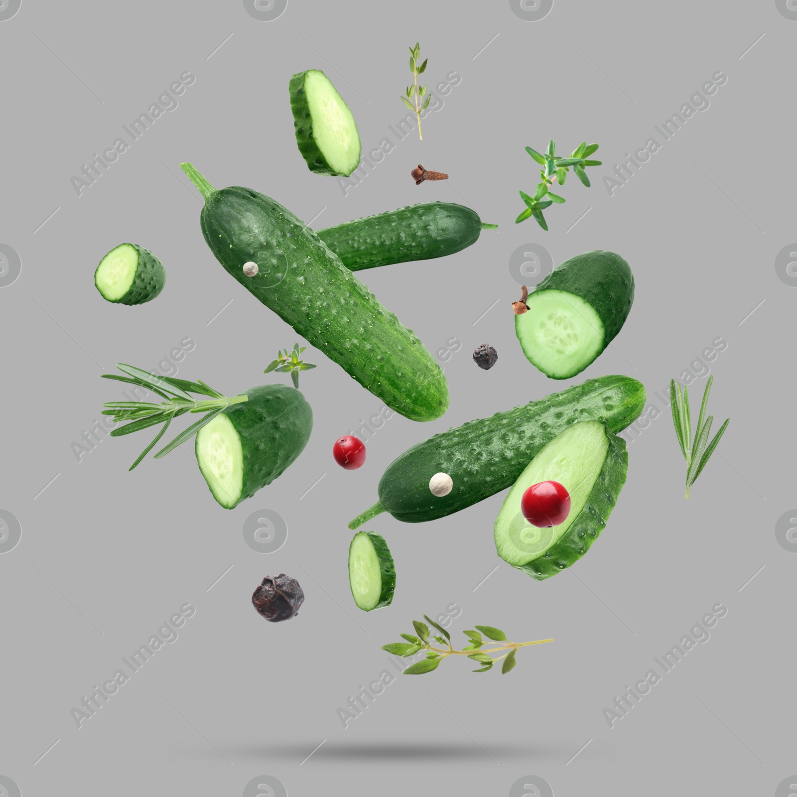 Image of Ripe cucumbers, herbs and spices falling on grey background