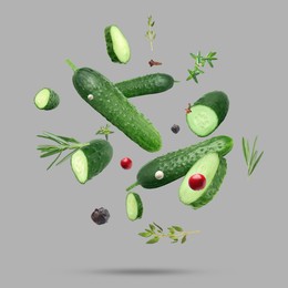 Image of Ripe cucumbers, herbs and spices falling on grey background