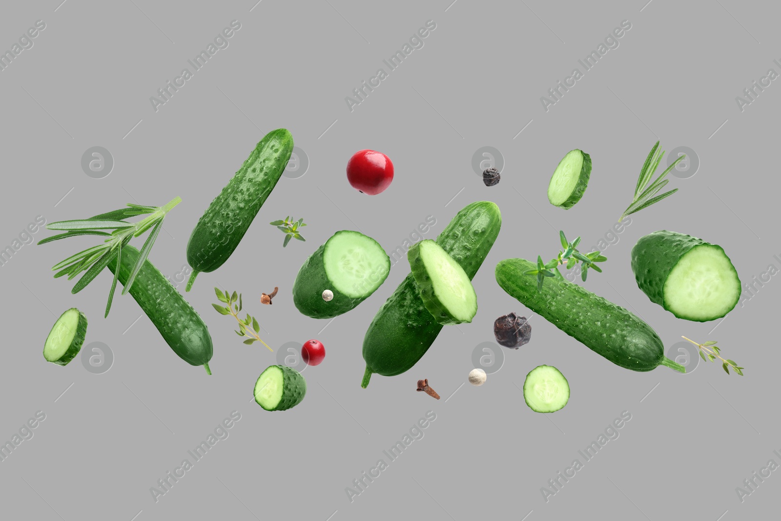 Image of Ripe cucumbers, herbs and spices flying on grey background