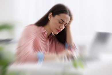 Image of Woman suffering from headache indoors, motion blur effect