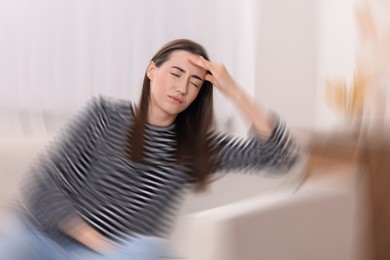 Image of Woman suffering from headache indoors, motion blur effect