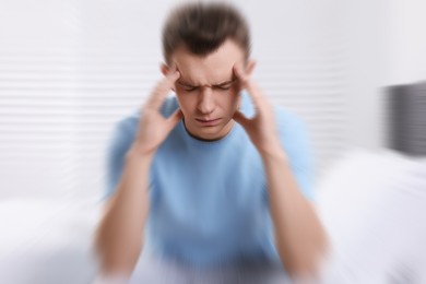 Man suffering from headache indoors, motion blur effect