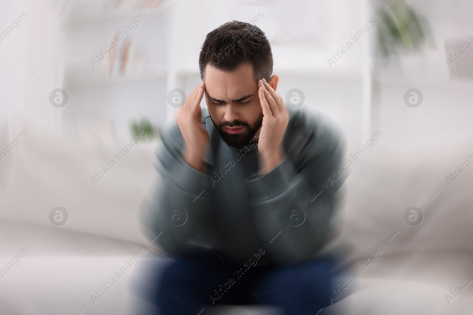 Image of Man suffering from headache indoors, motion blur effect