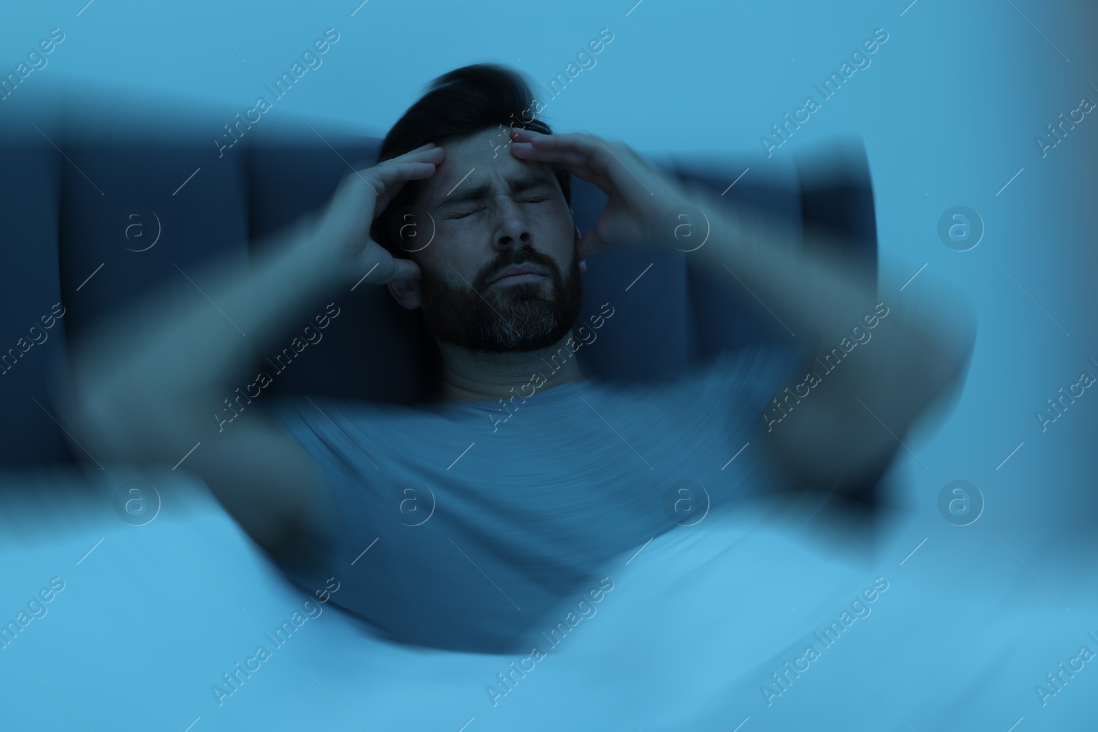 Image of Man suffering from headache in bed, motion blur effect