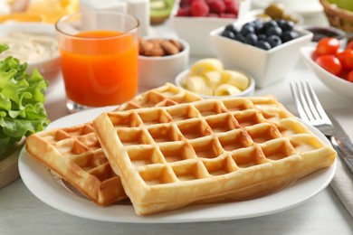 Photo of Tasty breakfast. Belgian waffles and other food on light table, closeup