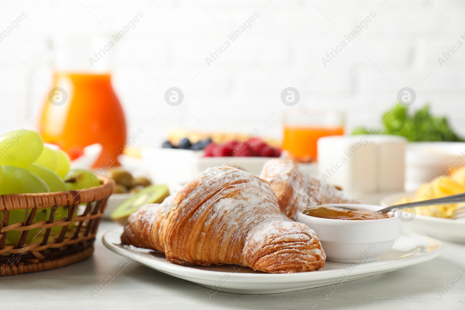 Photo of Tasty breakfast. Croissants, jam and other food on light table, closeup