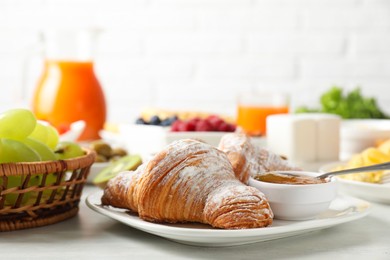 Photo of Tasty breakfast. Croissants, jam and other food on light table, closeup