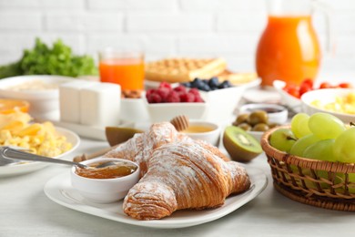 Photo of Tasty breakfast. Croissants, jam and other food on light table, closeup