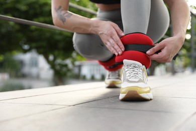 Woman putting on ankle weights outdoors, closeup