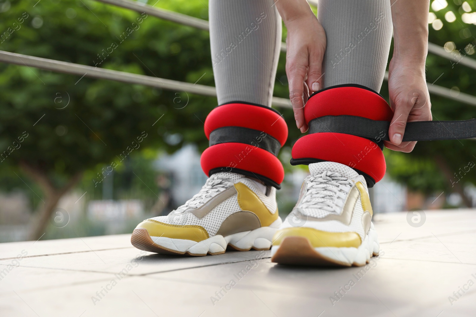 Photo of Woman putting on ankle weights outdoors, closeup