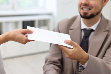 Smiling employee receiving envelope with salary from boss in office, closeup