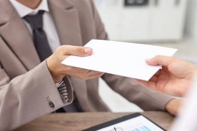 Photo of Employee receiving envelope with salary from boss in office, closeup