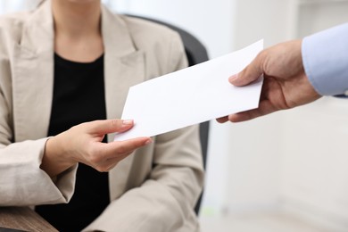 Photo of Employee receiving envelope with salary from boss in office, closeup