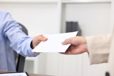 Employee receiving envelope with salary from boss in office, closeup