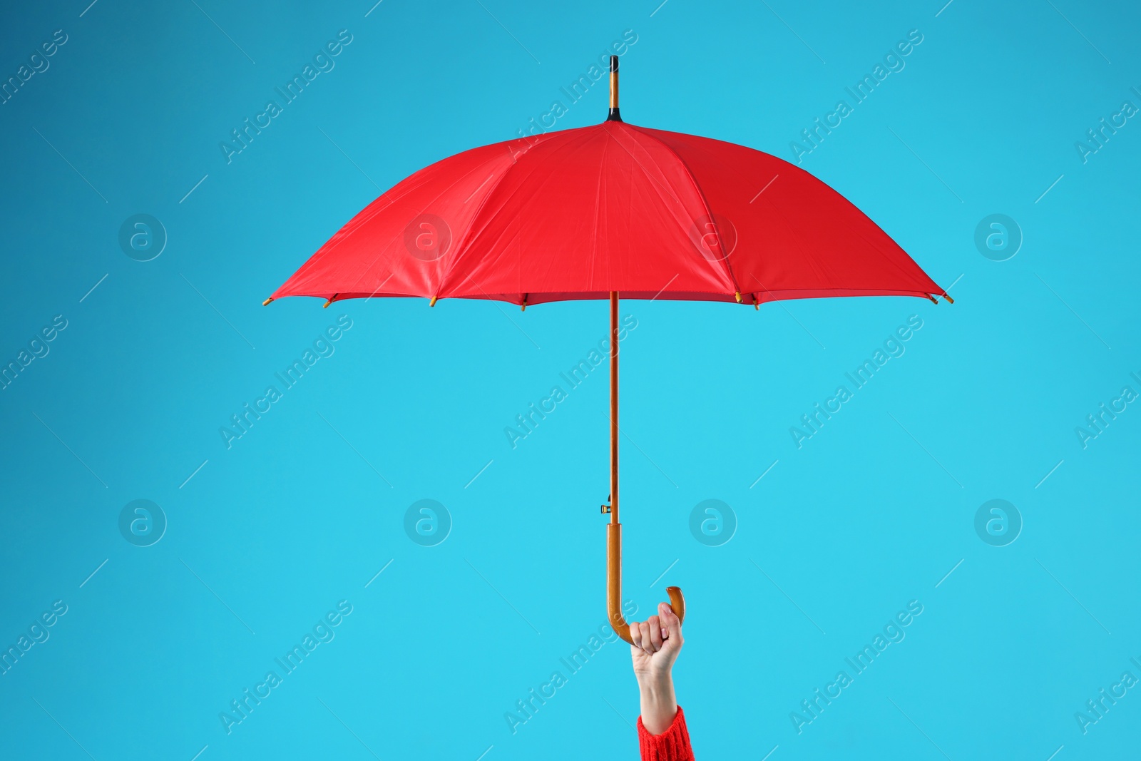 Photo of Woman with red umbrella on light blue background, closeup