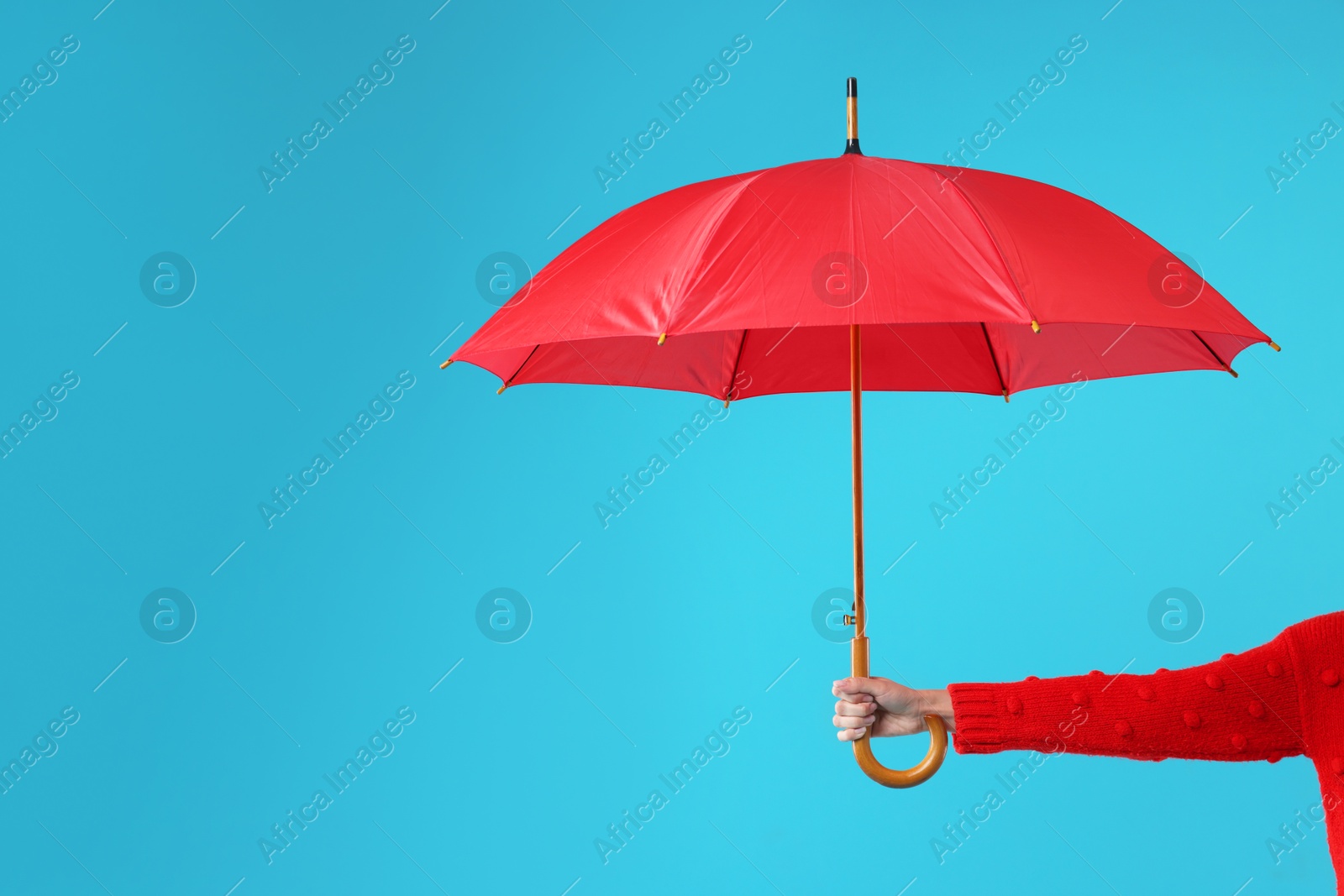 Photo of Woman with red umbrella on light blue background, closeup