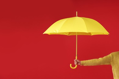 Woman with yellow umbrella on red background, closeup