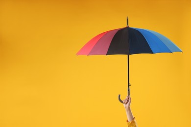 Woman with colorful umbrella on yellow background, closeup. Space for text