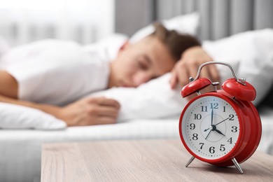 Photo of Man sleeping in bed at lunch time, focus on alarm clock