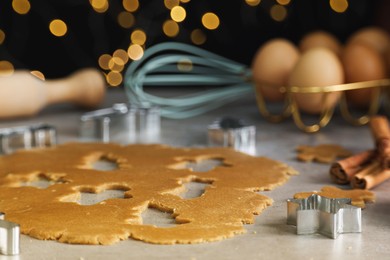 Photo of Raw dough, cookie cutters and cinnamon sticks on grey table, closeup