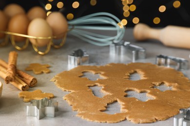 Photo of Raw dough, cookie cutters and cinnamon sticks on grey table, closeup