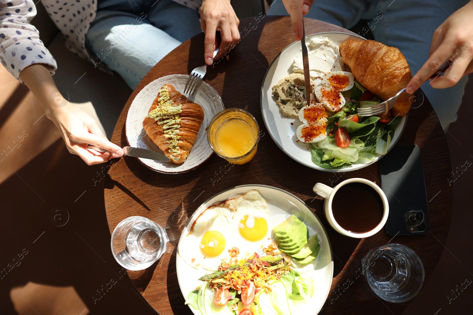 Photo of Couple having tasty breakfast at wooden table in cafe, top view