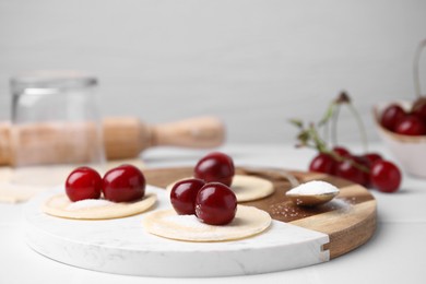 Process of making dumplings (varenyky) with cherries. Raw dough and ingredients on white table