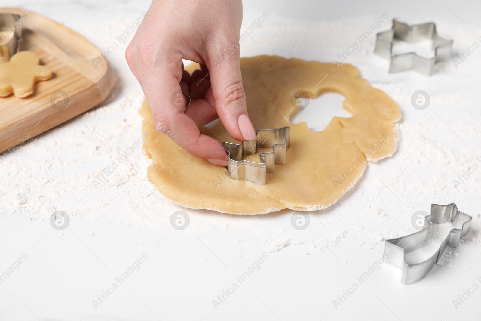 Photo of Woman making cookies with cutters at white table, closeup