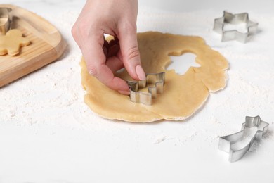 Woman making cookies with cutters at white table, closeup