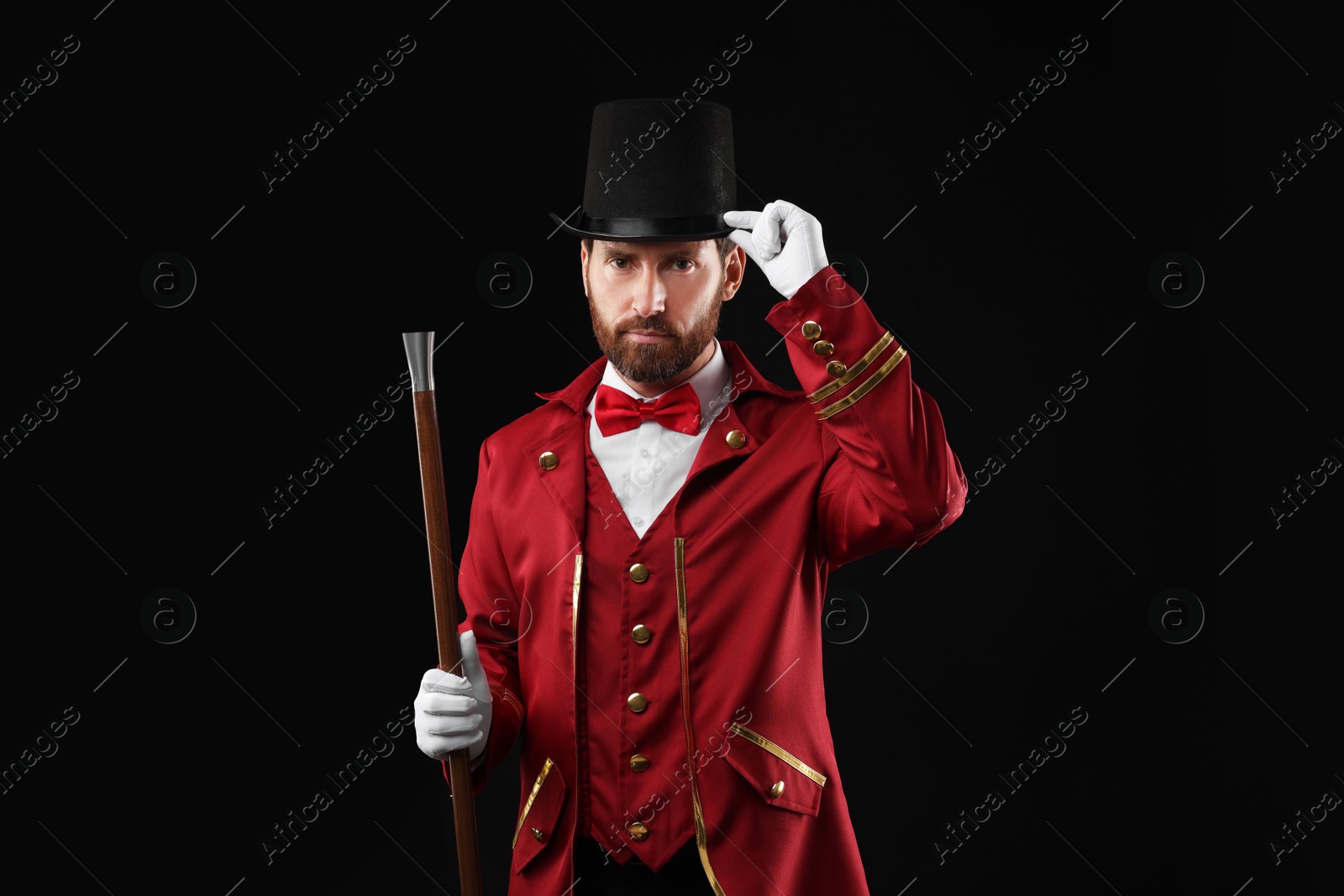 Photo of Portrait of showman in red costume and hat on black background