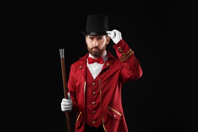 Portrait of showman in red costume and hat on black background