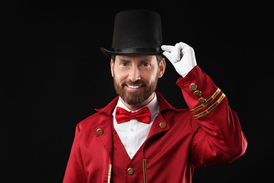 Photo of Portrait of showman in red costume and hat on black background