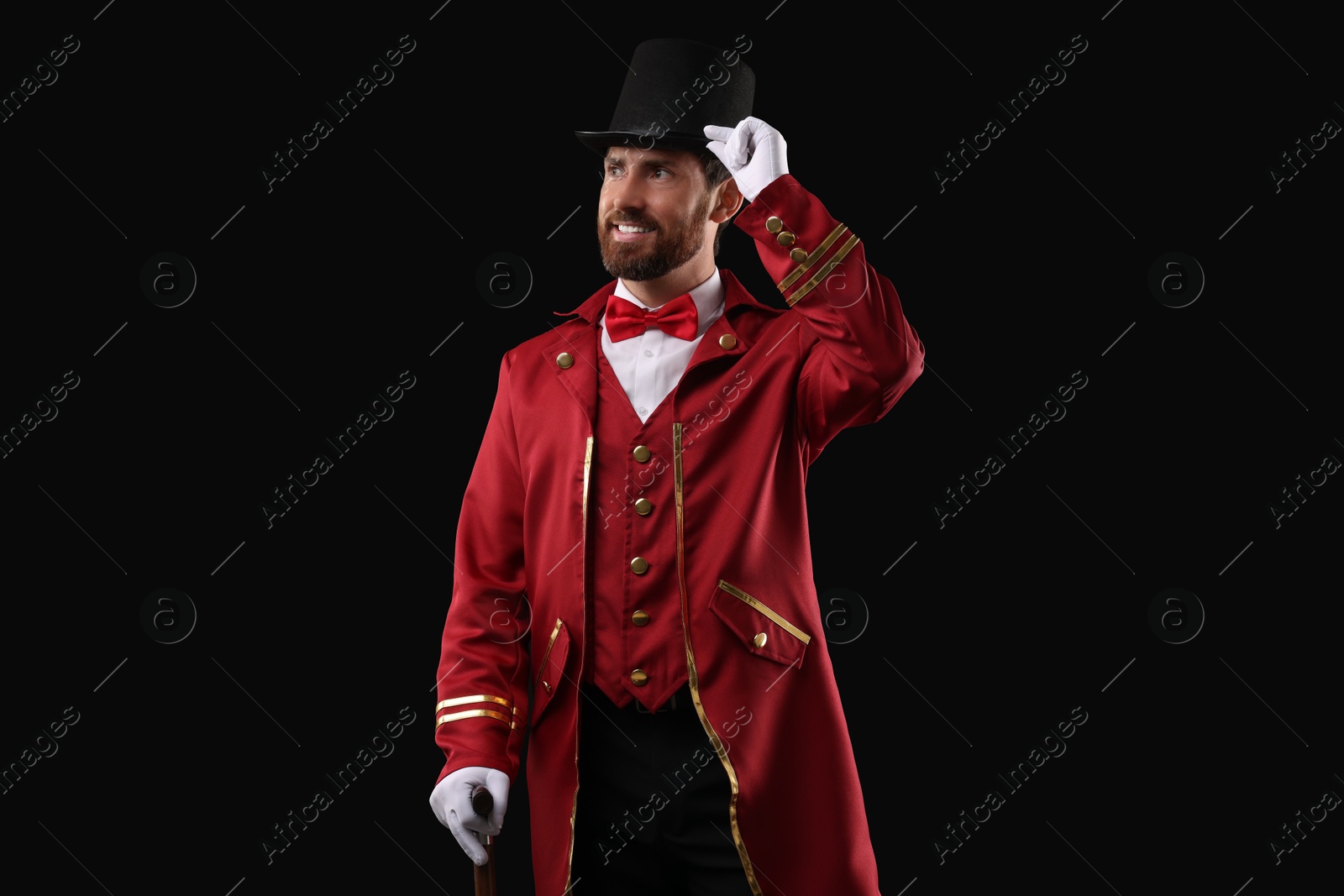 Photo of Portrait of showman in red costume and hat on black background