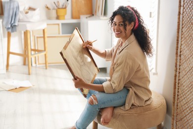 Photo of Smiling woman drawing picture with pencil in studio