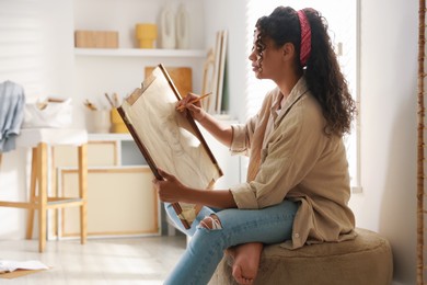 Beautiful woman drawing portrait with pencil in studio