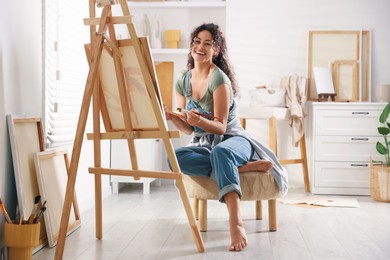 Smiling woman drawing picture on canvas in studio