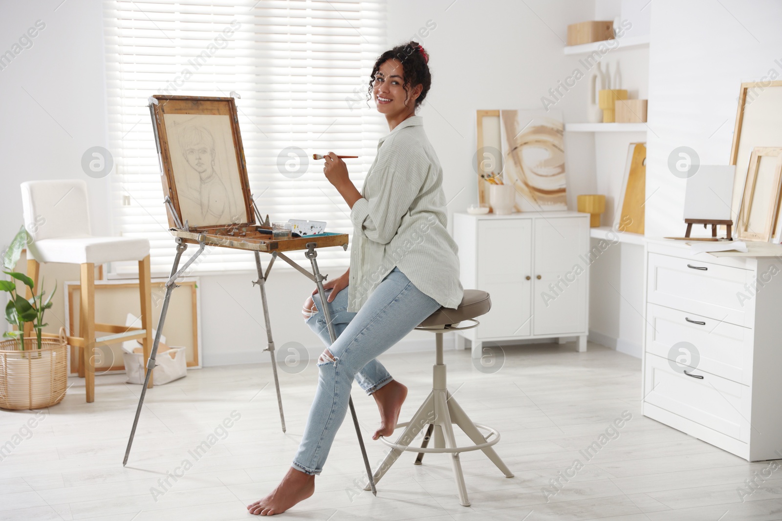 Photo of Smiling woman drawing picture on canvas in studio