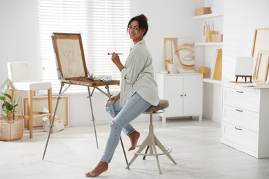 Photo of Smiling woman drawing picture on canvas in studio