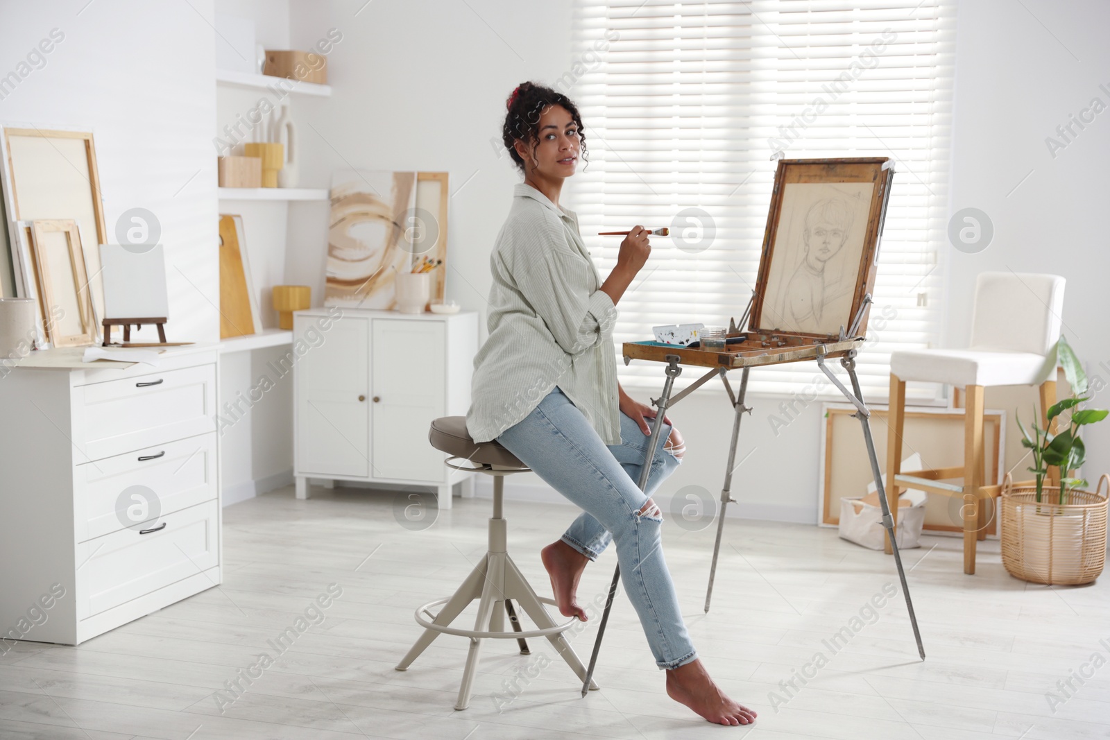 Photo of Beautiful woman drawing picture on canvas in studio