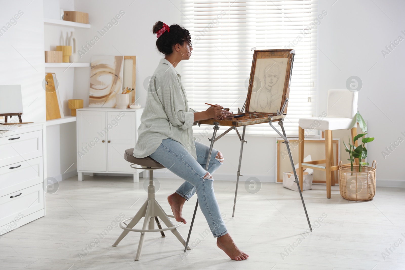 Photo of Beautiful woman drawing picture on canvas in studio