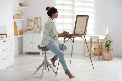 Beautiful woman drawing picture on canvas in studio