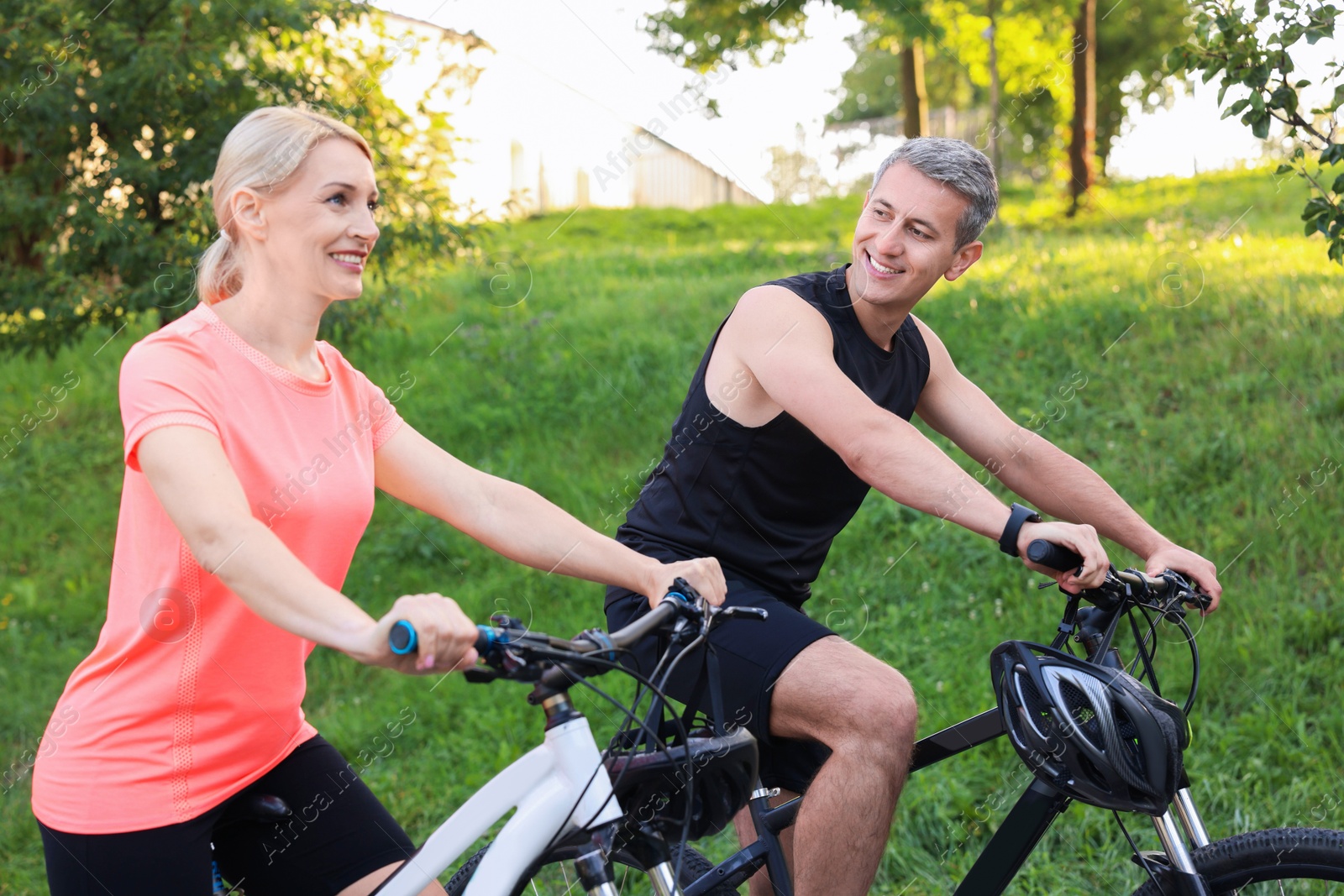 Photo of Happy couple riding bicycles in park. Healthy lifestyle