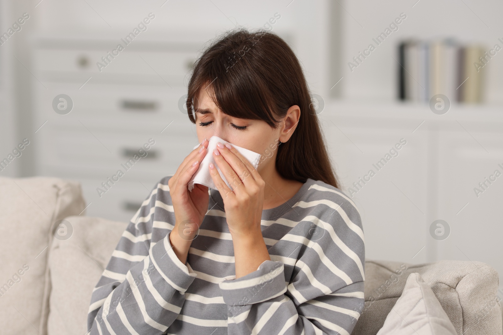 Photo of Woman with napkin suffering from sinusitis on sofa at home