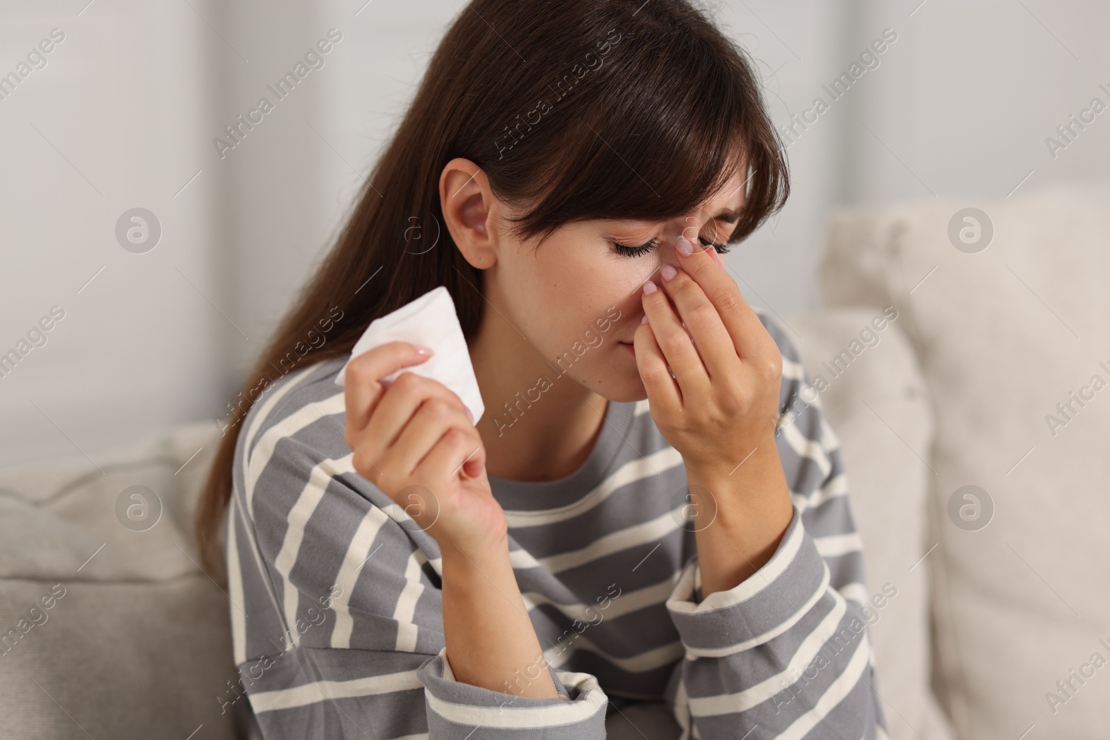 Photo of Woman with napkin suffering from sinusitis on sofa at home