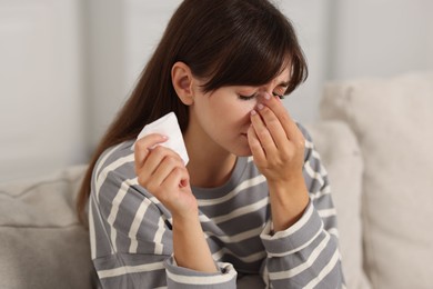 Photo of Woman with napkin suffering from sinusitis on sofa at home